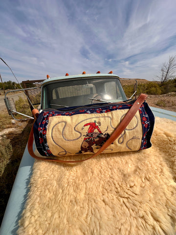 Decorative horse blanket gear bag with a rider design on a truck bed against a natural landscape.